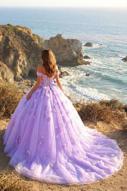 Lavender ball gown with floral appliqué, off-shoulder design, overlooking ocean cliffs.