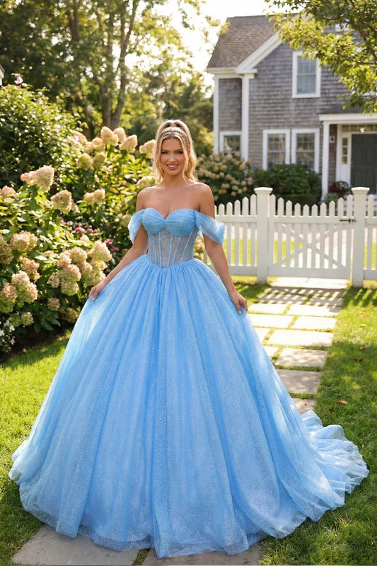 Woman in a blue off-shoulder ball gown dress with a full tulle skirt posing in a garden