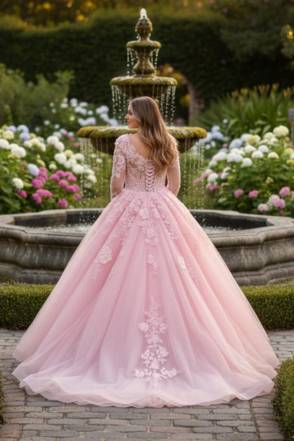 Pink long sleeve ball gown with floral lace, worn by a woman in a garden by a fountain.