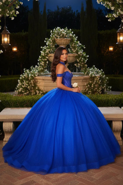 Woman in royal blue off-the-shoulder ball gown posing by garden fountain at night