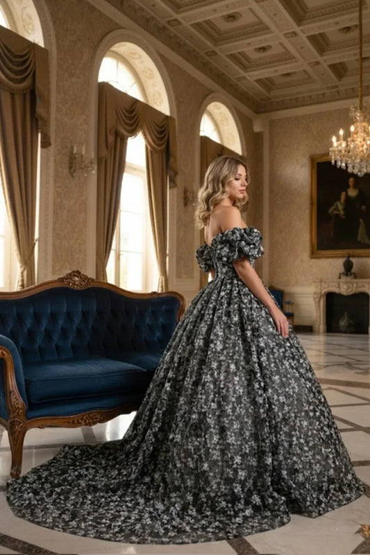 Woman in elegant off-the-shoulder ball gown with floral pattern in a grand, luxurious room