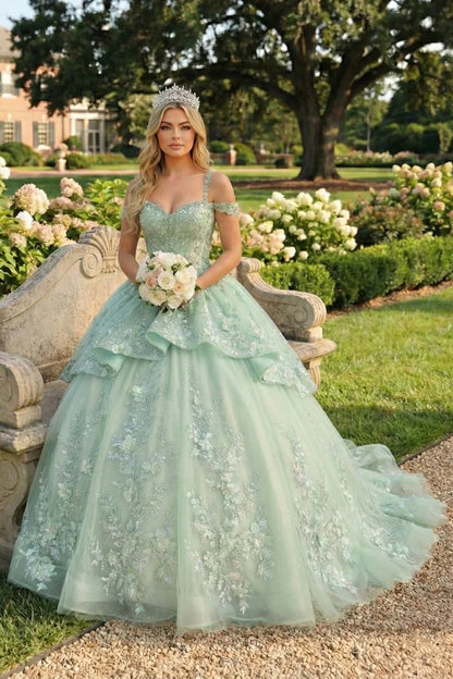Woman in mint green ball gown with floral embroidery, crown, and bouquet in a garden setting