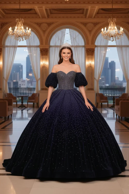 Woman in navy blue sparkle ball gown with cold-shoulder sleeves and tiara in elegant hall