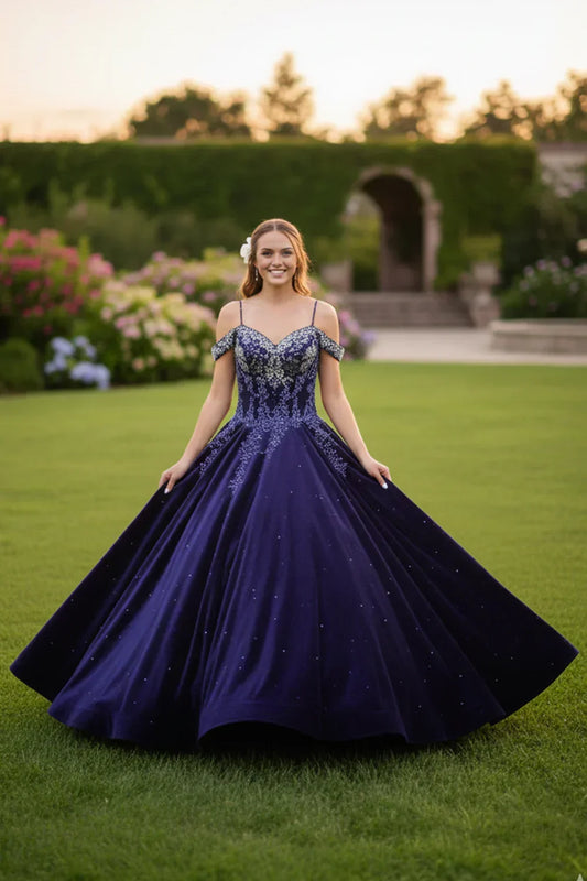 Elegant navy blue lace ball gown with cold shoulder design and sparkle details, worn outdoors